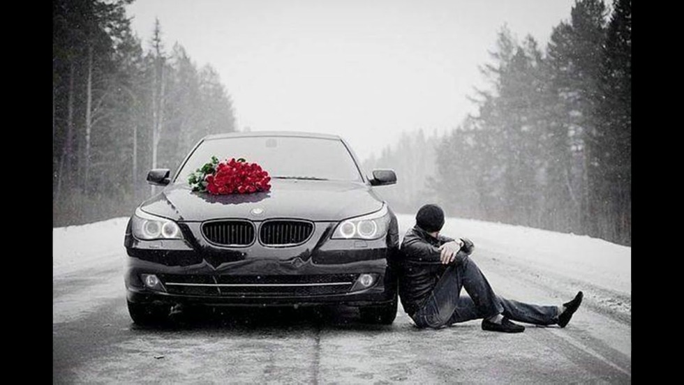 A guy with flowers by car