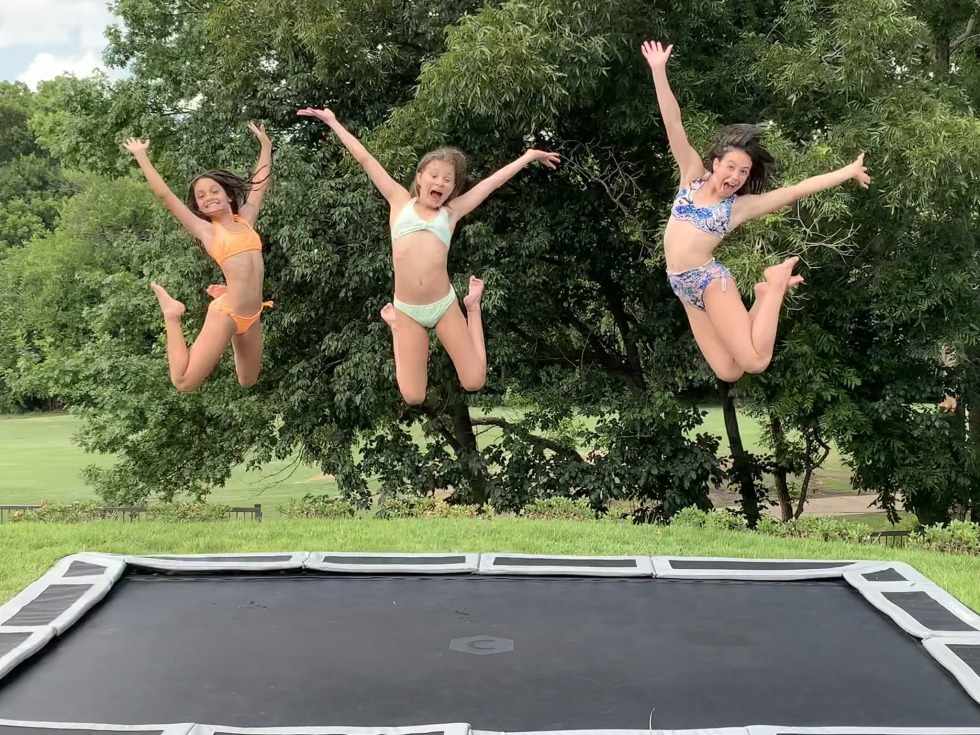 Girls with bare breasts jump on a trampoline