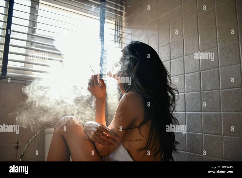 The girl smokes on the windowsill