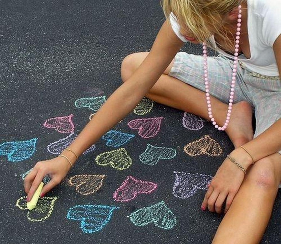 The girl draws on the asphalt