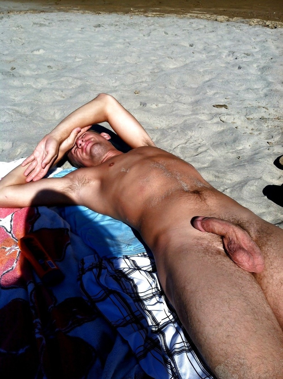 A naked man lies on the beach