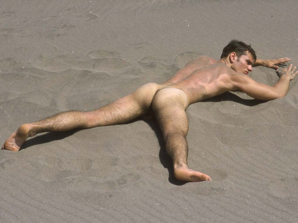 A naked guy lies on the beach